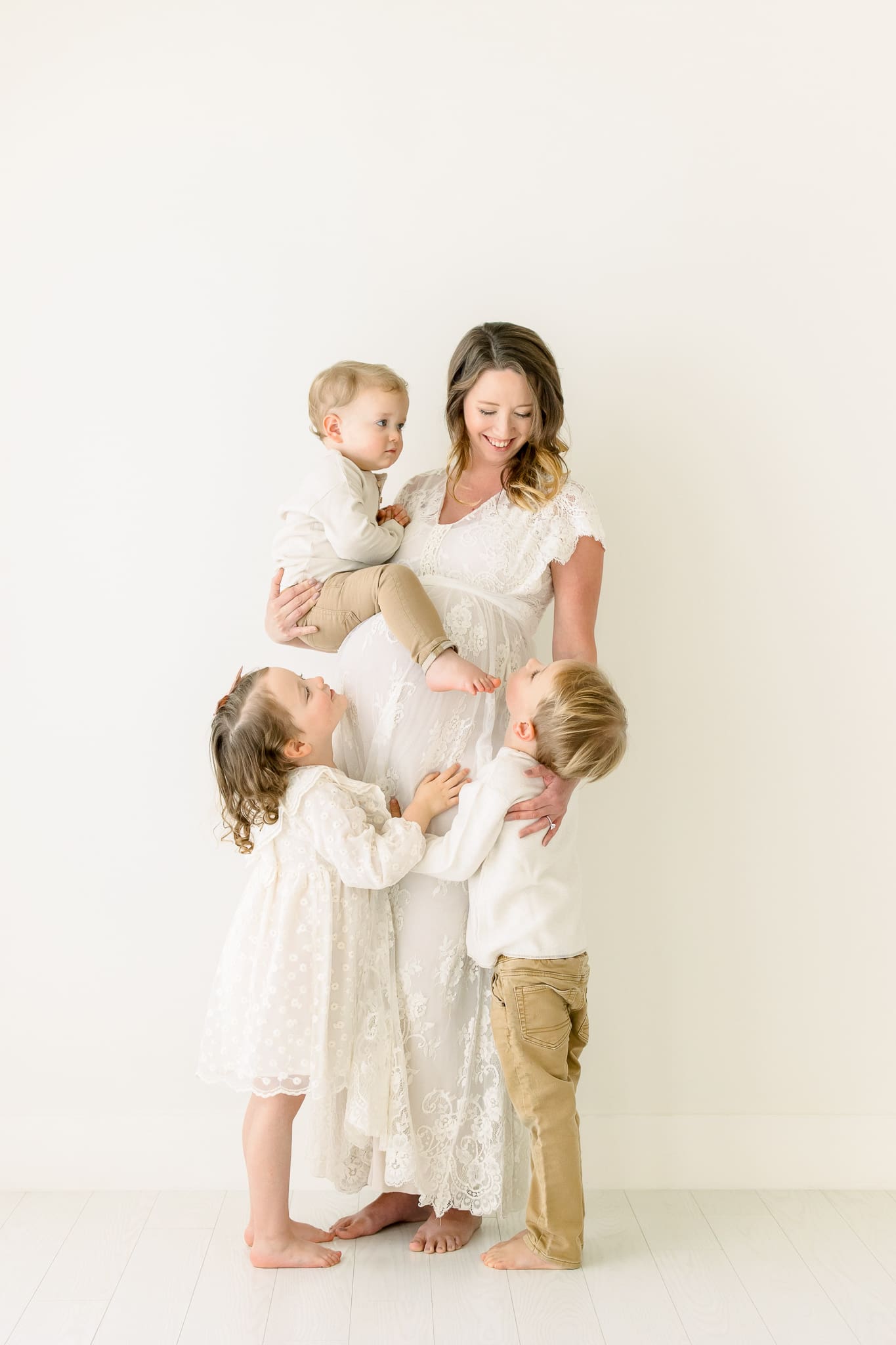 a pregnant mother with her other 3 children all around her, smiling